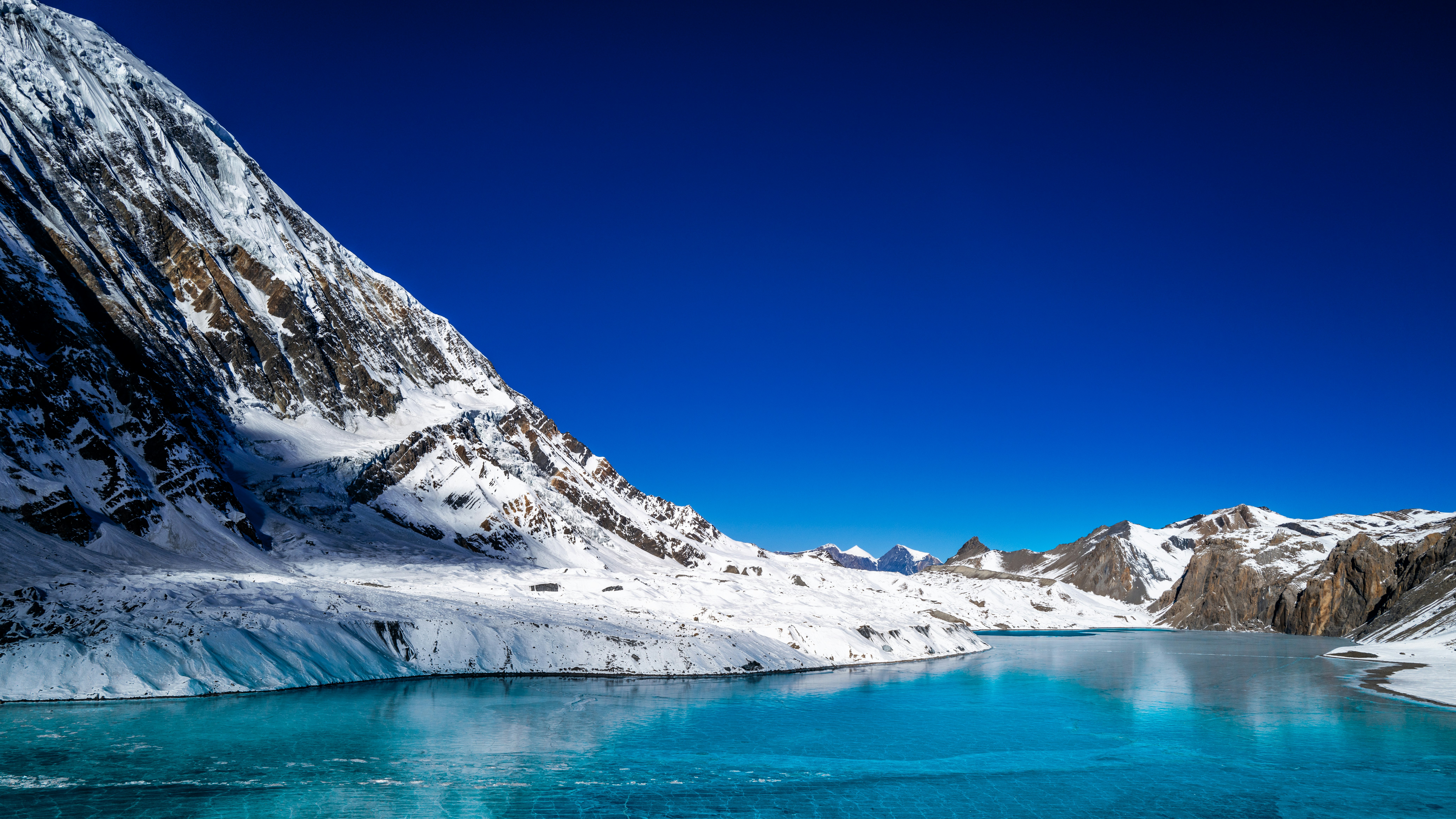 Snowy mountains overlook a bright blue glacial lake.