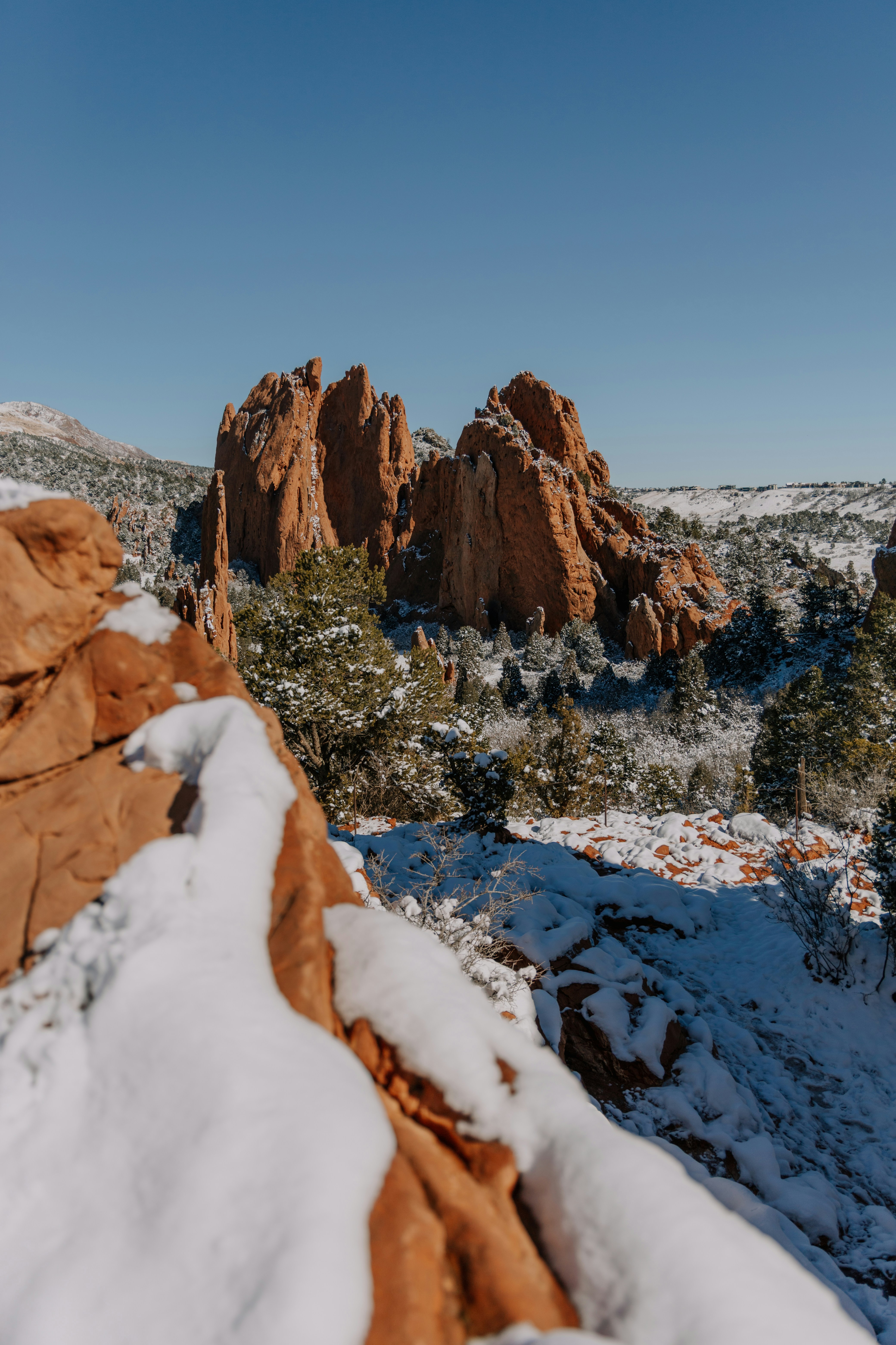 Snow-covered red rock formations under a clear blue sky.